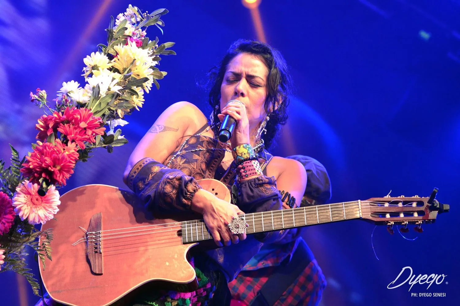 Lila Downs cantando con guitarra y flores